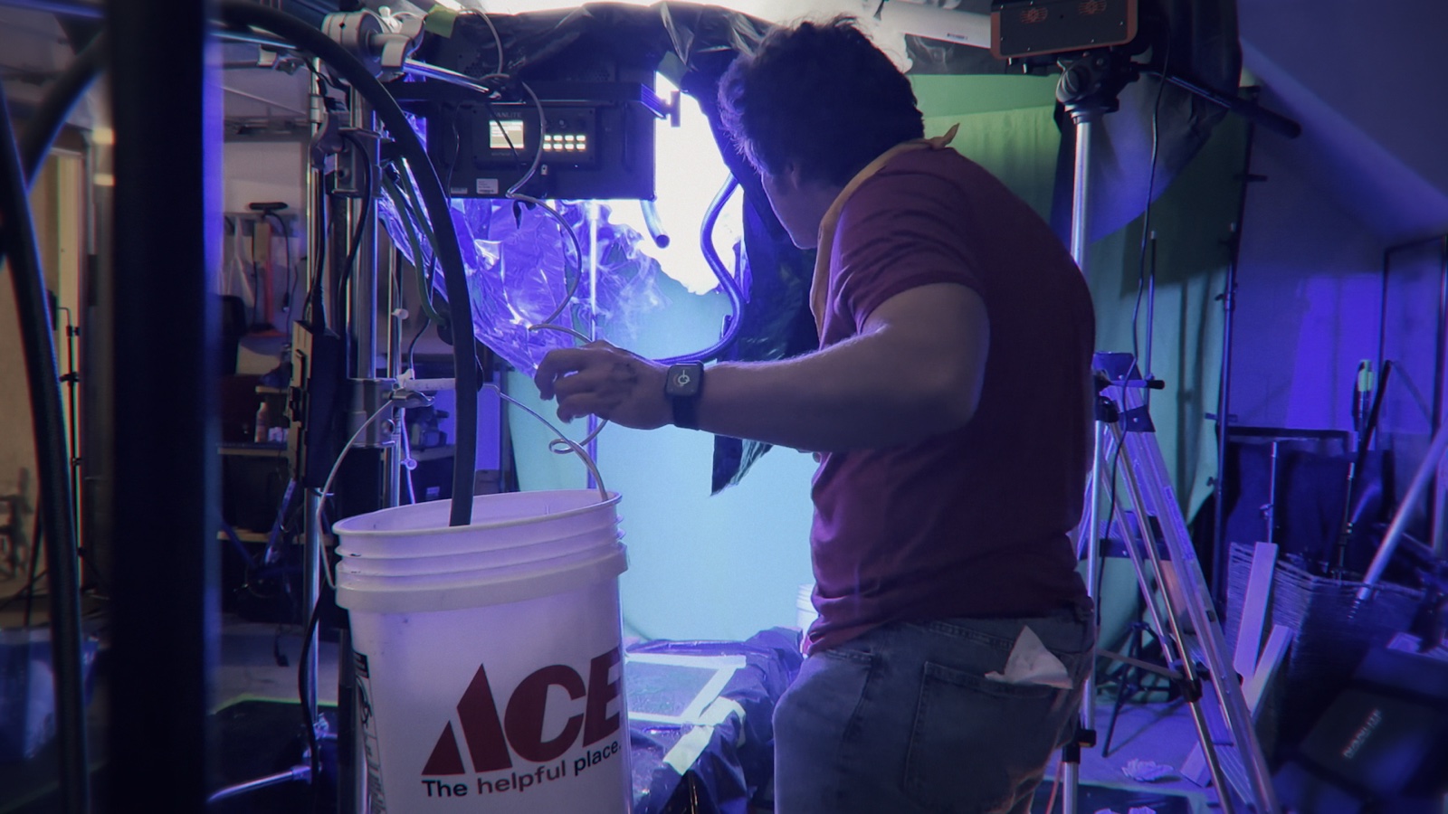 Burt creating practical motion in water above an Ace Hardware bucket while the camera records.