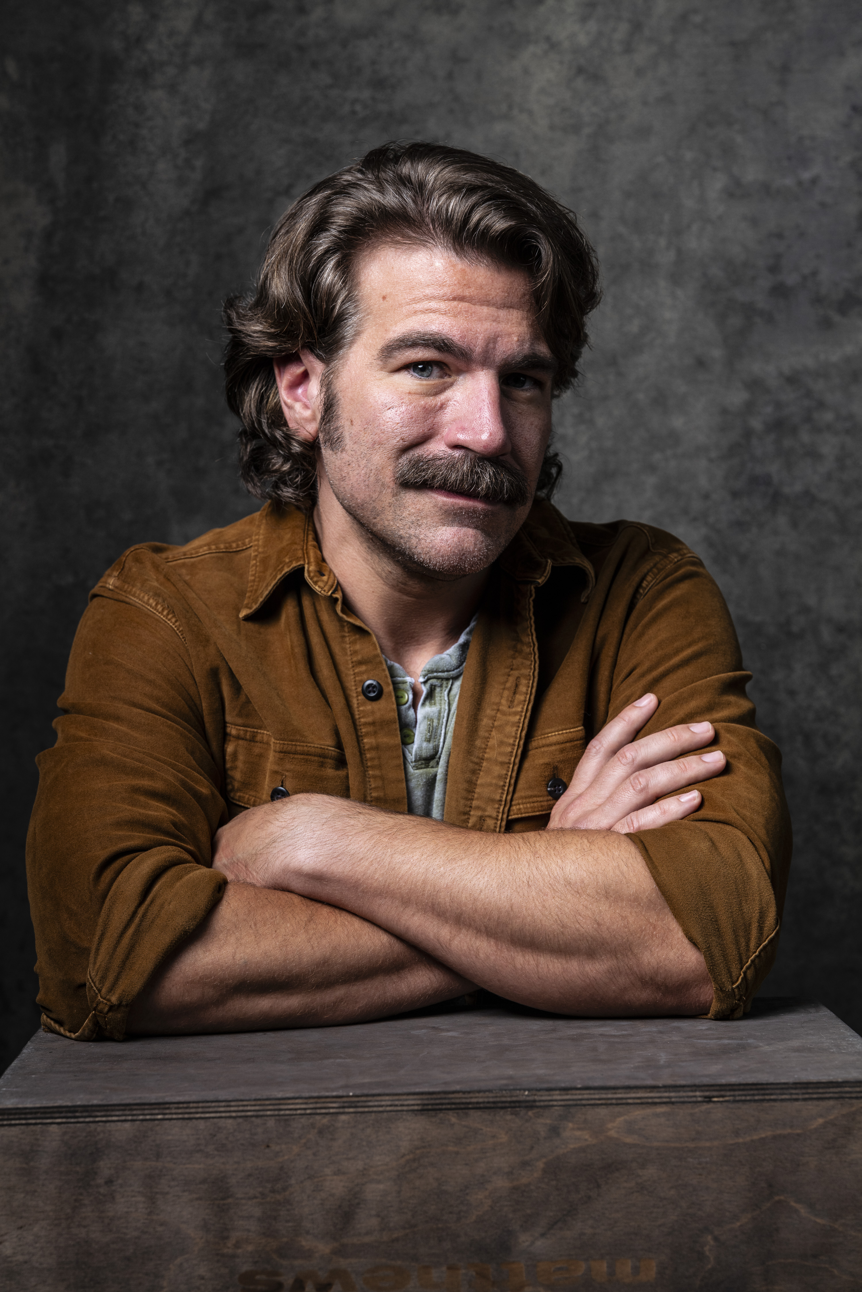 Burt Rutherford, leaning forward with his arms folded and a slight smile.